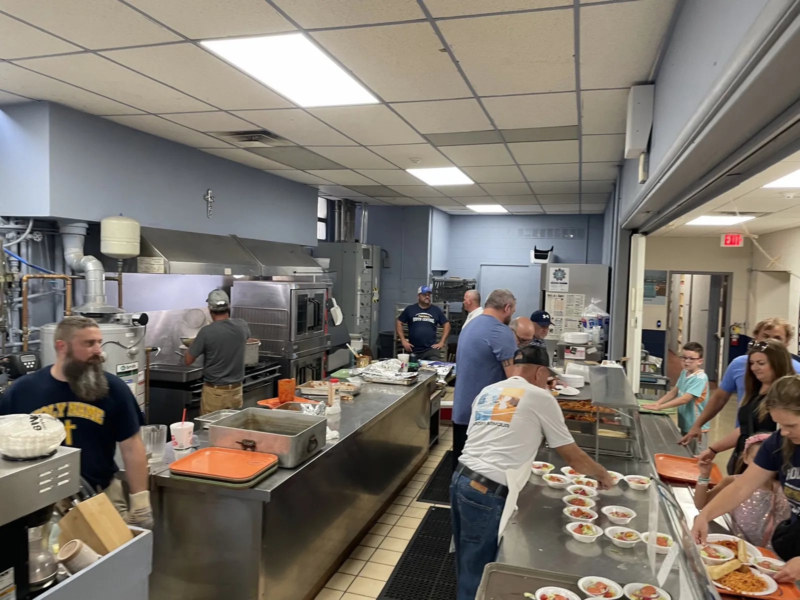 Holy Name Men’s Club volunteers working the kitchen line, plating salads and spaghetti